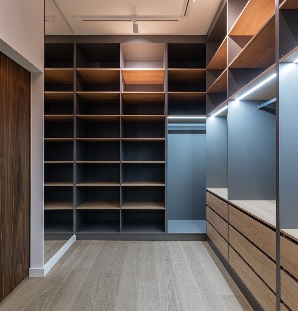Interior of modern spacious wardrobe room with empty shelves near door and mirror