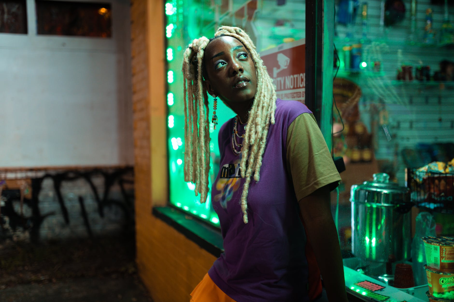 black girl with blonde locs standing outside a store at night